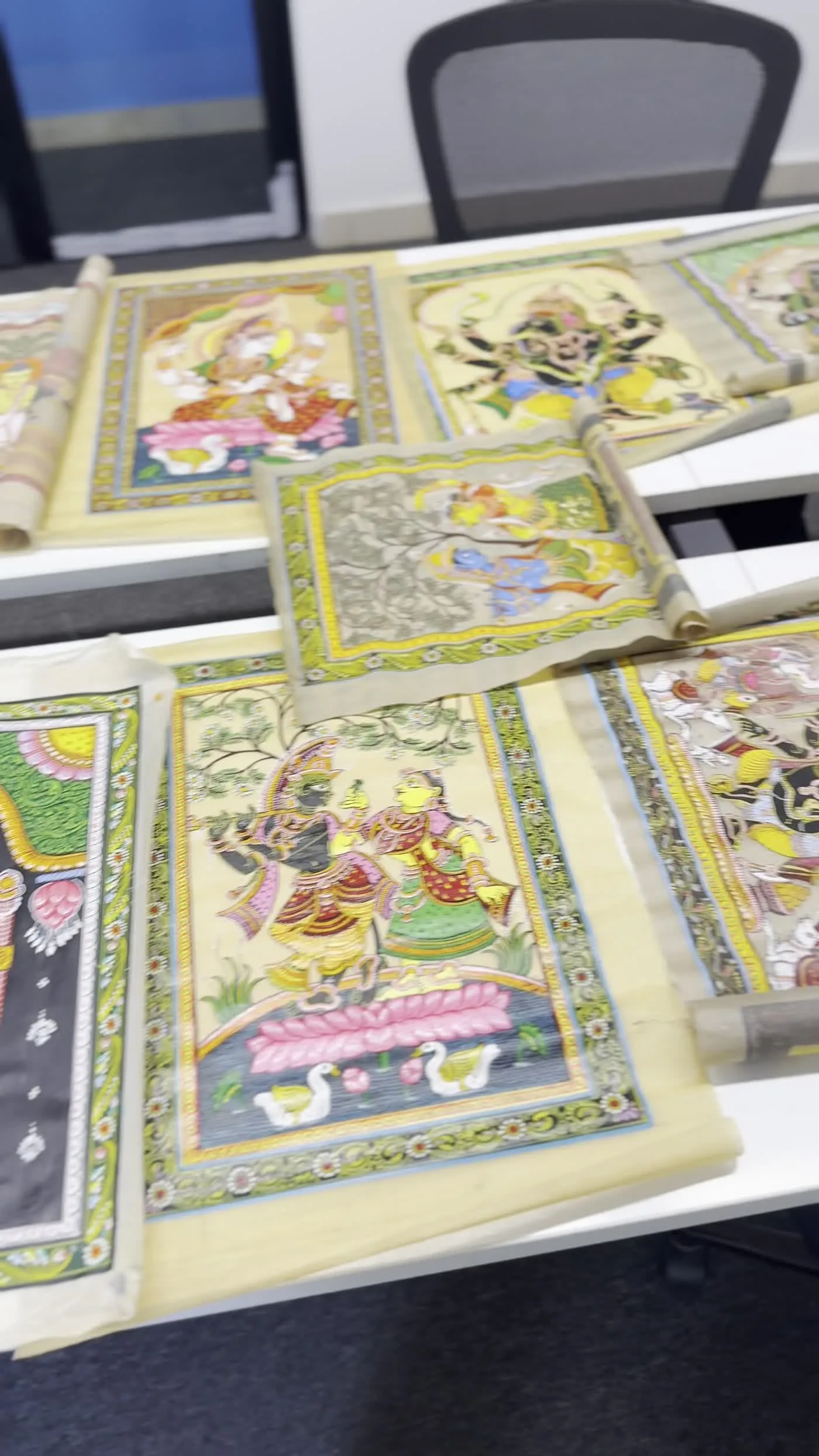 Pattachitra scroll paintings laid out on a table, including a Jagannath, Balabhadra, and Subhadra panel